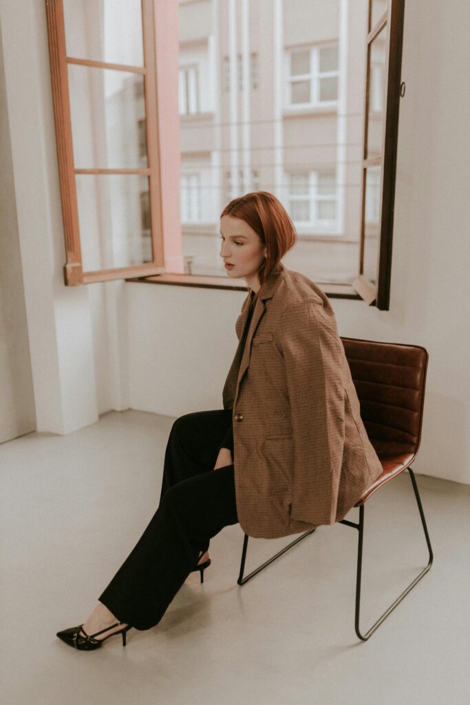 Red-haired girl sitting in chair by window